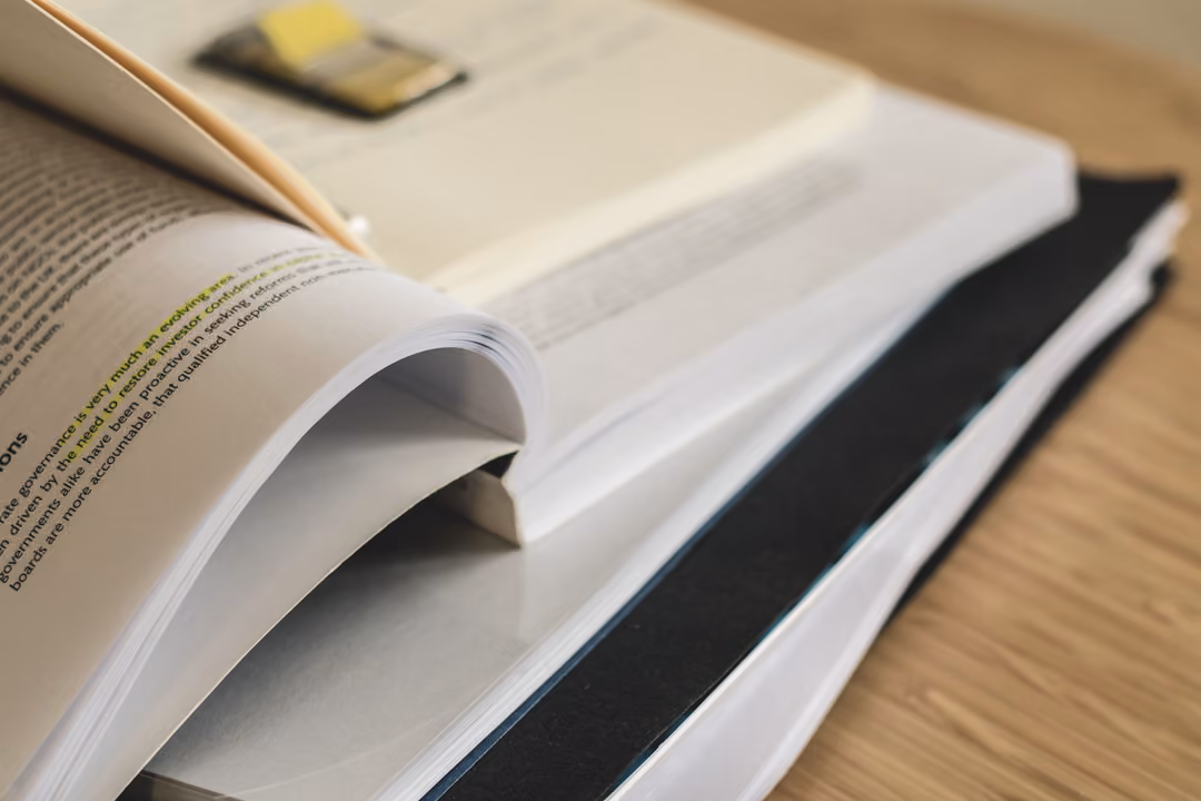 An open textbook on corporate governance, mid-page, on a wooden desk with soft natural light.